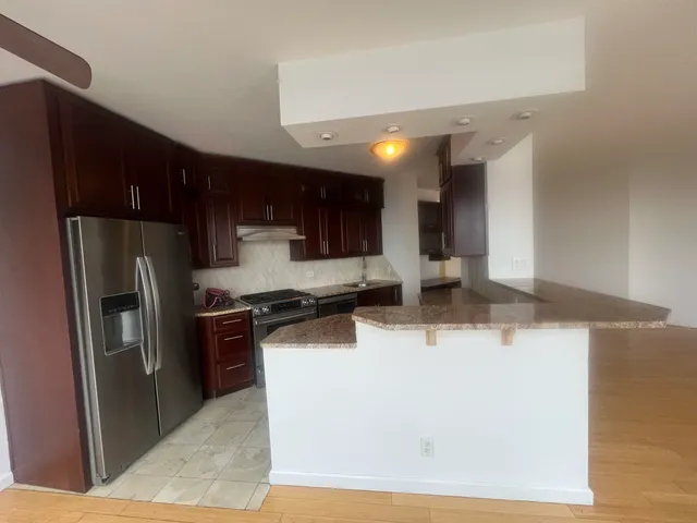 a kitchen with stainless steel appliances a sink a stove a refrigerator a center island and furniture