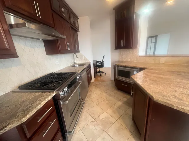 a kitchen with stainless steel appliances granite countertop a stove a sink and a microwave