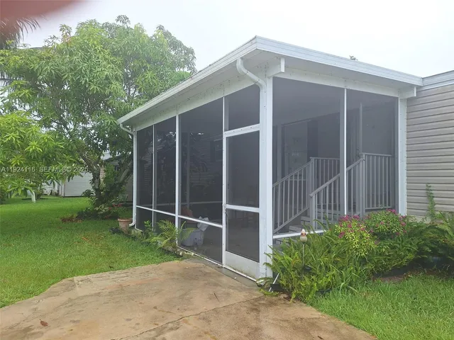 a backyard of a house with plants and large tree