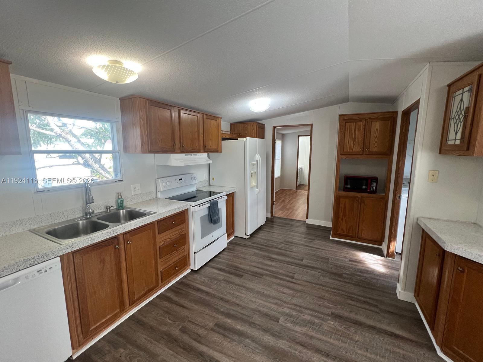 35303 Southwest 180th Avenue, Unit 399 Homestead, FL 33034 - Photo 3 of 16 a kitchen with granite countertop a refrigerator and a sink