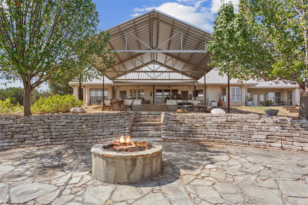 564 Sam Bass Road McGregor, TX 76657 - Photo 24 of 37 Expansive outdoor living area featuring a stone fire pit, flagstone patio, and a stone retaining wall