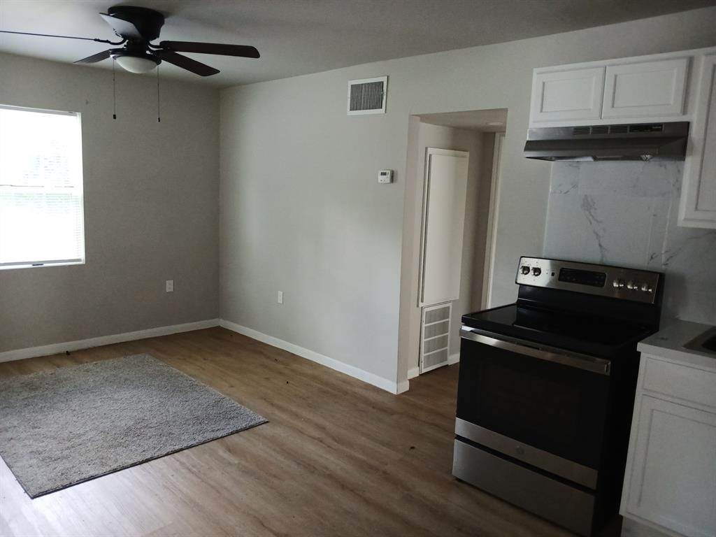 15519 Highway 6 Santa Fe, TX 77517 - Photo 10 of 14 an empty room with wooden floor cabinet and windows