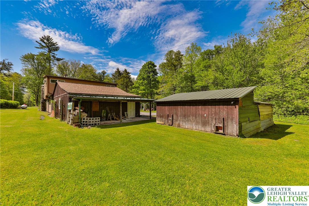 331 Cranberry Creek Road Cresco, PA 18326 - Photo 68 of 95 A rustic residence and adjacent barn sit nestled in a vibrant green landscape, offering serene rural living.