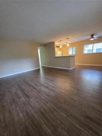 an empty room with wooden floor cabinet and windows