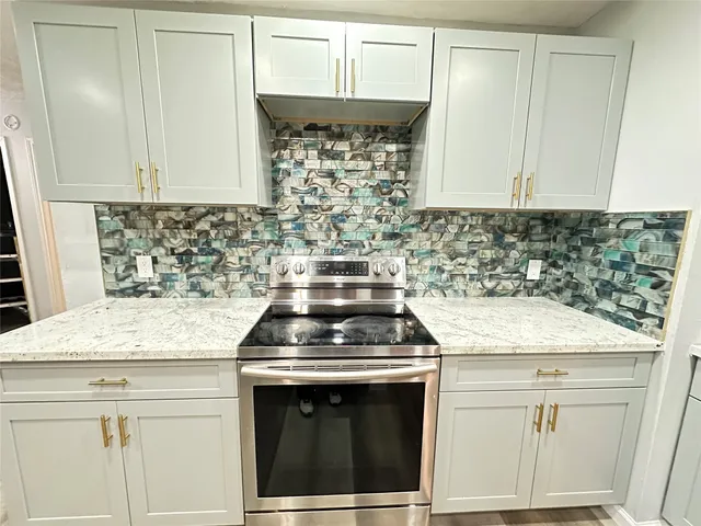 a kitchen with granite countertop white cabinets and a stove