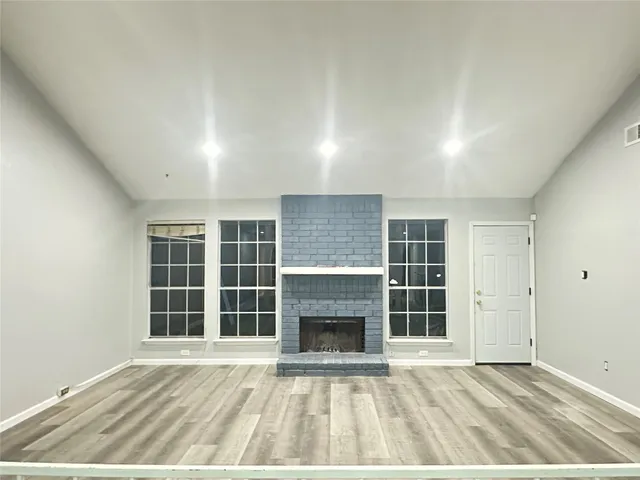 an empty room with windows and fireplace