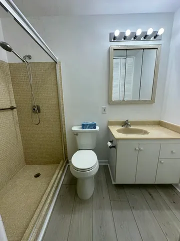 a bathroom with a granite countertop sink a toilet and shower
