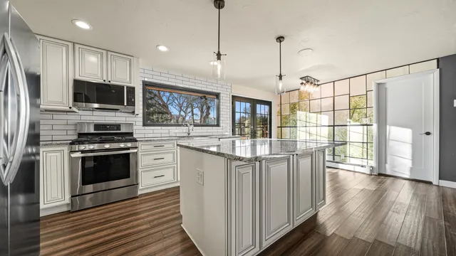 a kitchen with stainless steel appliances granite countertop a stove and a wooden floors