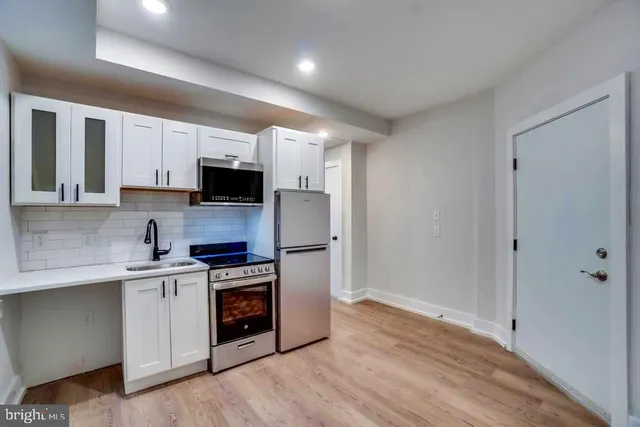 a kitchen with cabinets stainless steel appliances and wooden floor