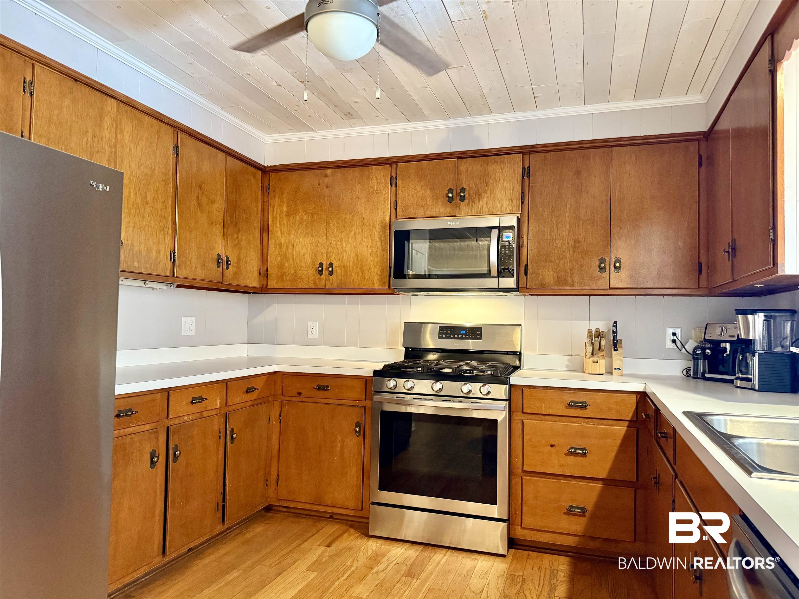 2785 Appleton Road Brewton, AL 36426 - Photo 13 of 28 Kitchen featuring stainless steel appliances, brown cabinetry, light countertops, light wood-style floors, and ornamental molding