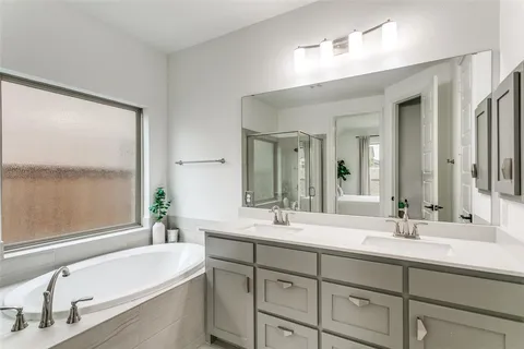 a bathroom with a double vanity sink mirror and a bathtub