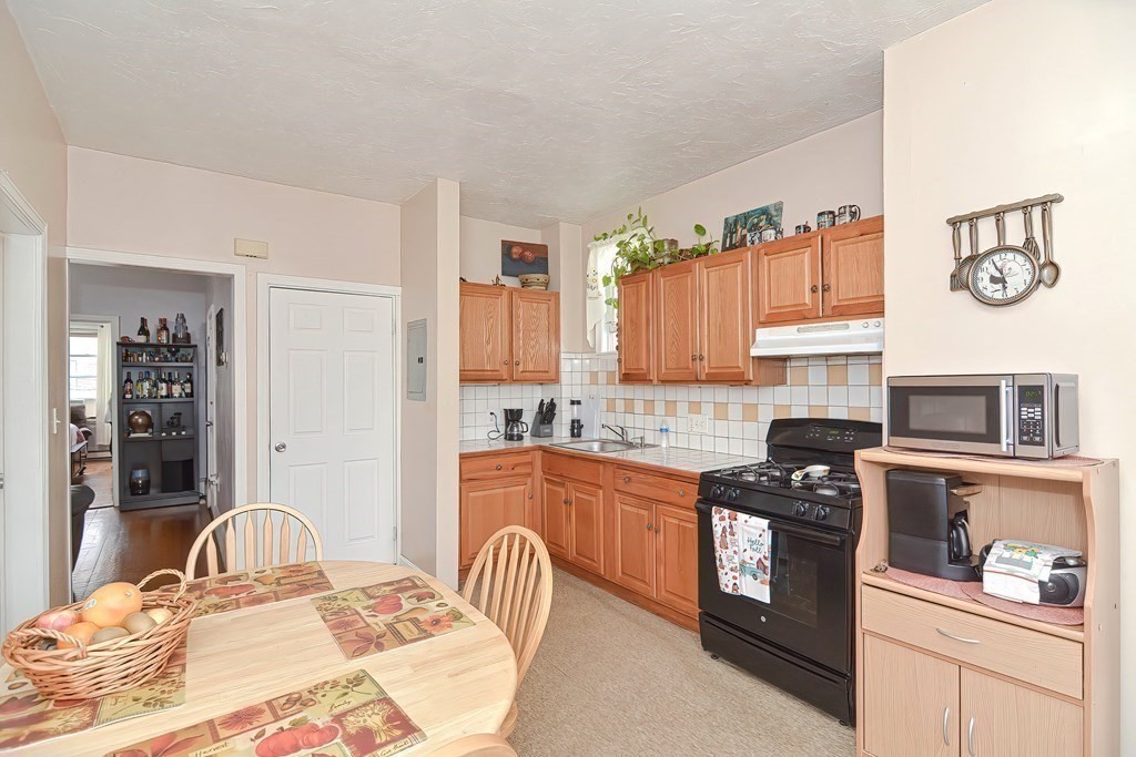 110 Everett Street Boston, MA 02128 - Photo 12 of 41 a kitchen with stainless steel appliances granite countertop a stove top oven a sink a dining table and chairs with wooden floor