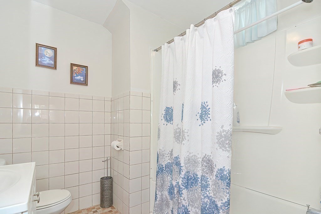 110 Everett Street Boston, MA 02128 - Photo 29 of 41 a white toilet sitting next to a shower curtain