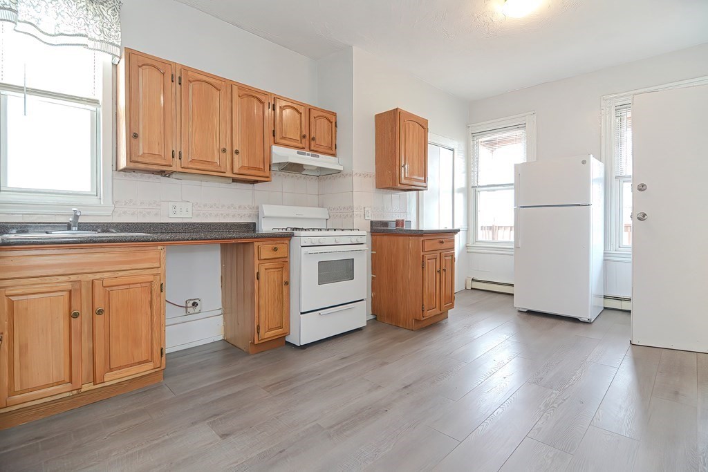 110 Everett Street Boston, MA 02128 - Photo 5 of 41 a kitchen with white cabinets and wooden floors