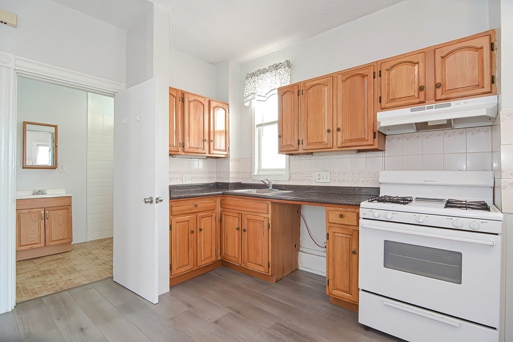 110 Everett Street Boston, MA 02128 - Photo 6 of 41 a kitchen with granite countertop wooden cabinets stainless steel appliances and a window