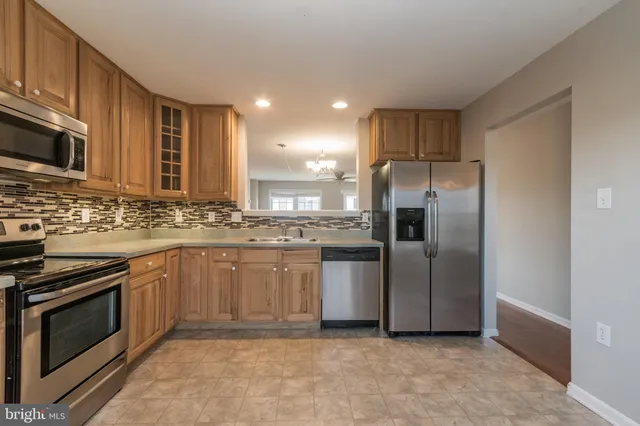 a kitchen with stainless steel appliances granite countertop a stove a sink and a refrigerator