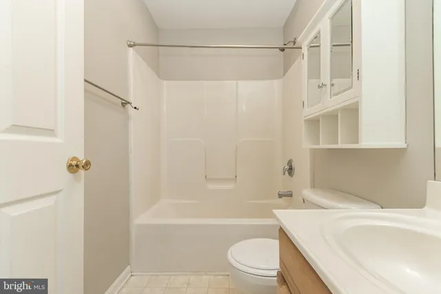 a bathroom with a granite countertop bathtub shower sink vanity and toilet