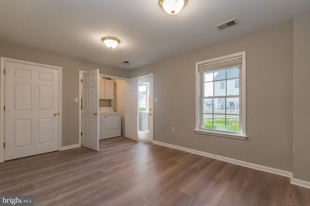 an empty room with wooden floor cabinet and windows