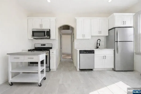 a kitchen with white cabinets and stainless steel appliances