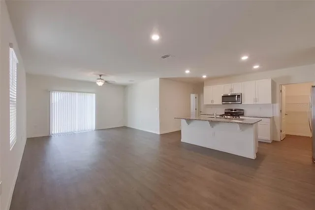a view of kitchen with kitchen island stainless steel appliances refrigerator stove microwave and cabinets