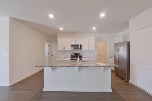 a large kitchen with stainless steel appliances granite countertop a sink a stove a refrigerator and cabinets