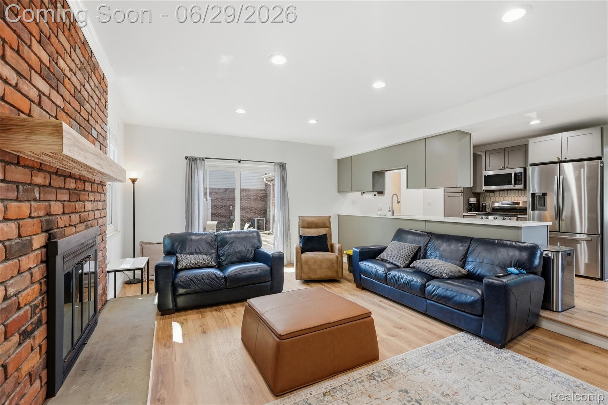 45179 Rudgate Road Canton, MI 48188 - Photo 10 of 48 Open-concept living space featuring a brick fireplace with a wood mantle, wood-finish flooring, recessed lighting, and sliding glass doors