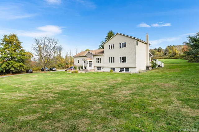 a view of white house with a big yard and large trees