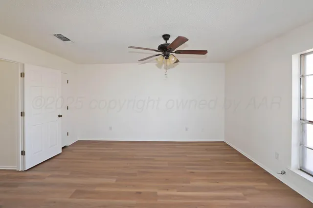 a view of a room with wooden floor and a ceiling fan