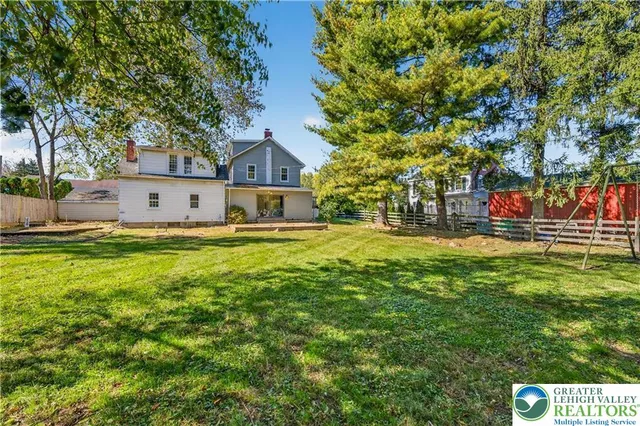 a view of a house with a big yard and large trees