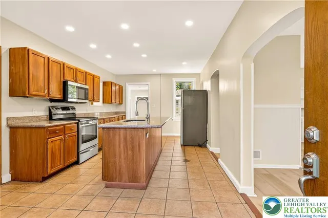 a large kitchen with stainless steel appliances granite countertop a refrigerator and a stove
