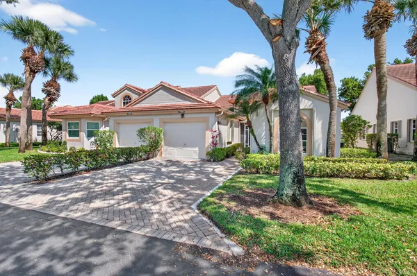 a view of a white house with a yard and palm trees