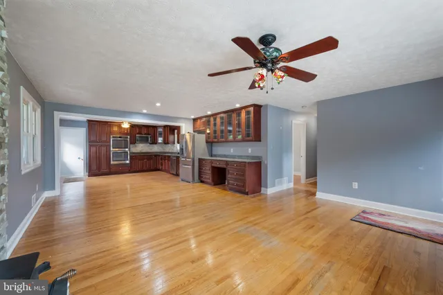 a view of a livingroom with a flat screen tv ceiling fan and a fireplace
