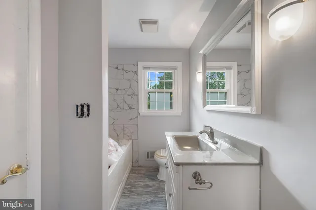 a bathroom with a granite countertop sink a toilet and shower