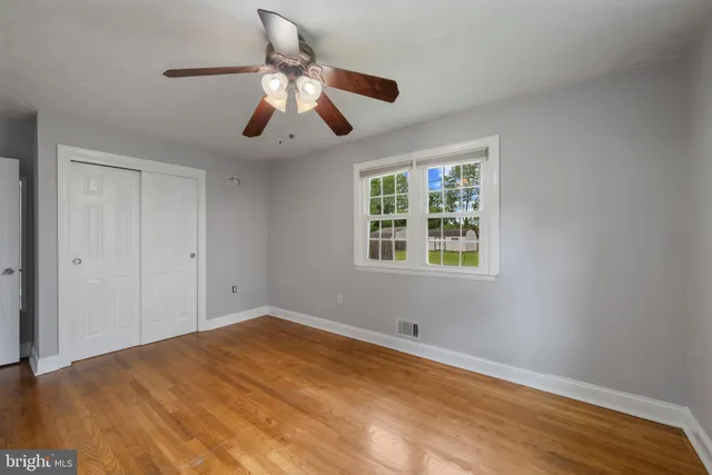 a view of an empty room with window and wooden floor