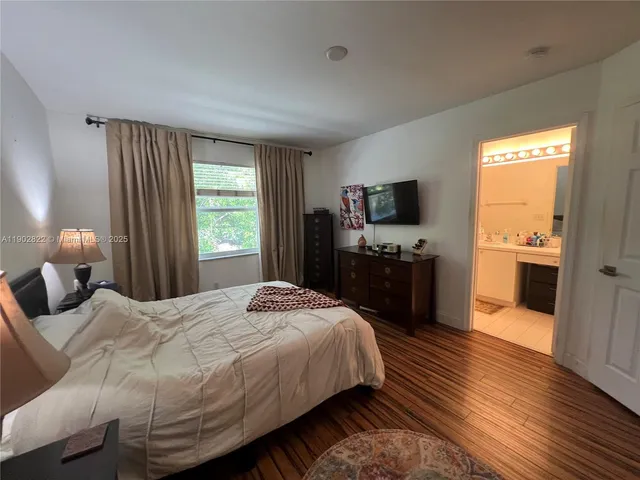 a bedroom with a bed and a flat tv screen on dresser