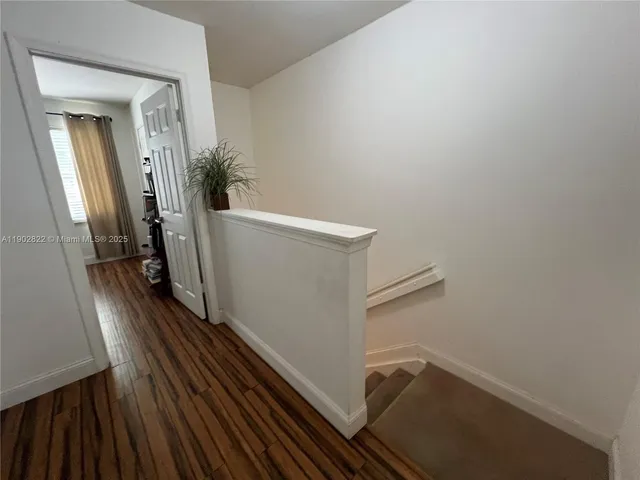a view of a hallway with wooden floor and stairs
