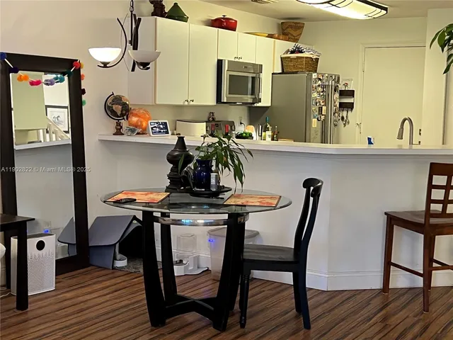 a room with stainless steel appliances kitchen island a table chairs in it and wooden floors