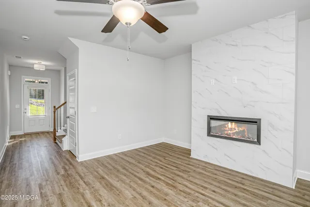 a view of an empty room with wooden floor and a ceiling fan