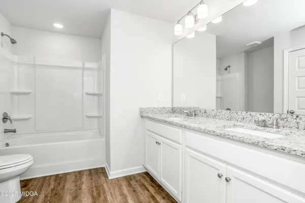 a bathroom with a granite countertop sink a toilet and shower