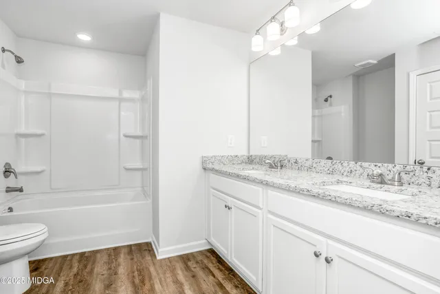 a bathroom with a granite countertop sink a toilet and shower