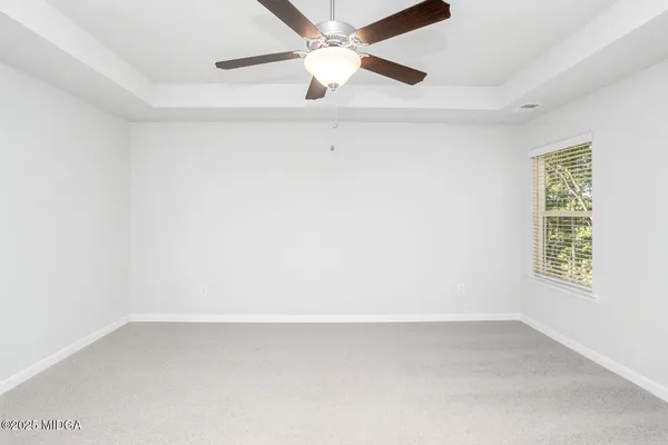 an empty room with a window and a ceiling fan