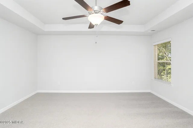 an empty room with a window and a ceiling fan