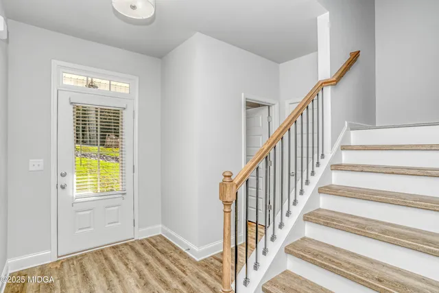 a view of a hallway with wooden floor and stairs