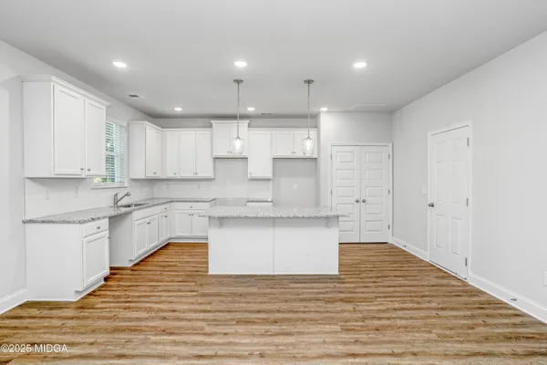 a large kitchen with granite countertop a white stove top oven and white cabinets