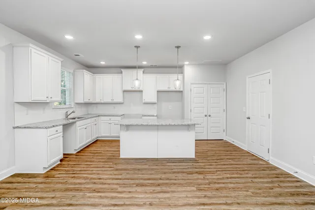 a large kitchen with granite countertop a white stove top oven and white cabinets