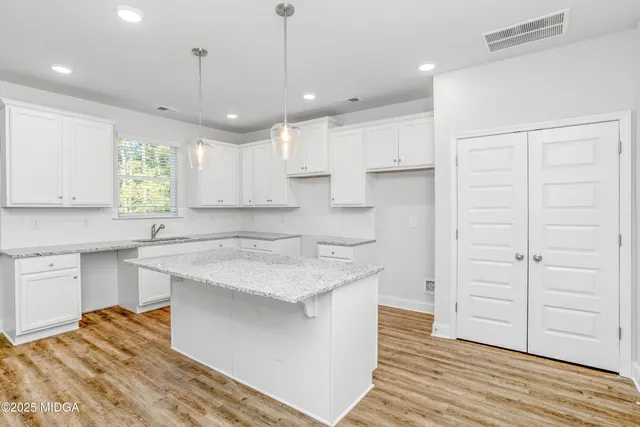 a kitchen with a sink dishwasher a stove a refrigerator and white cabinets with wooden floor