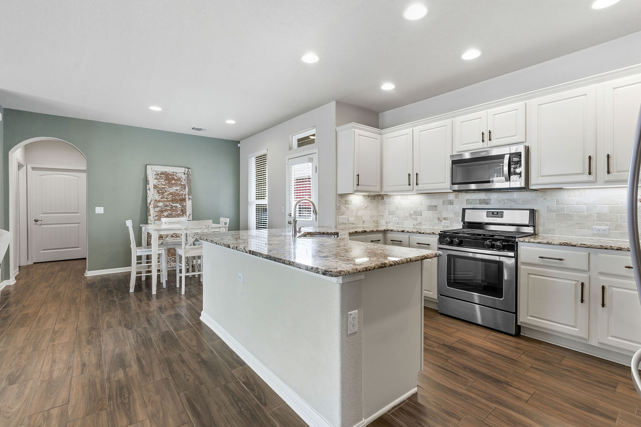 6005 Baythorne Drive Austin, TX 78747 - Photo 5 of 40 Kitchen featuring stainless steel appliances, white cabinetry, light stone countertops, and recessed lighting