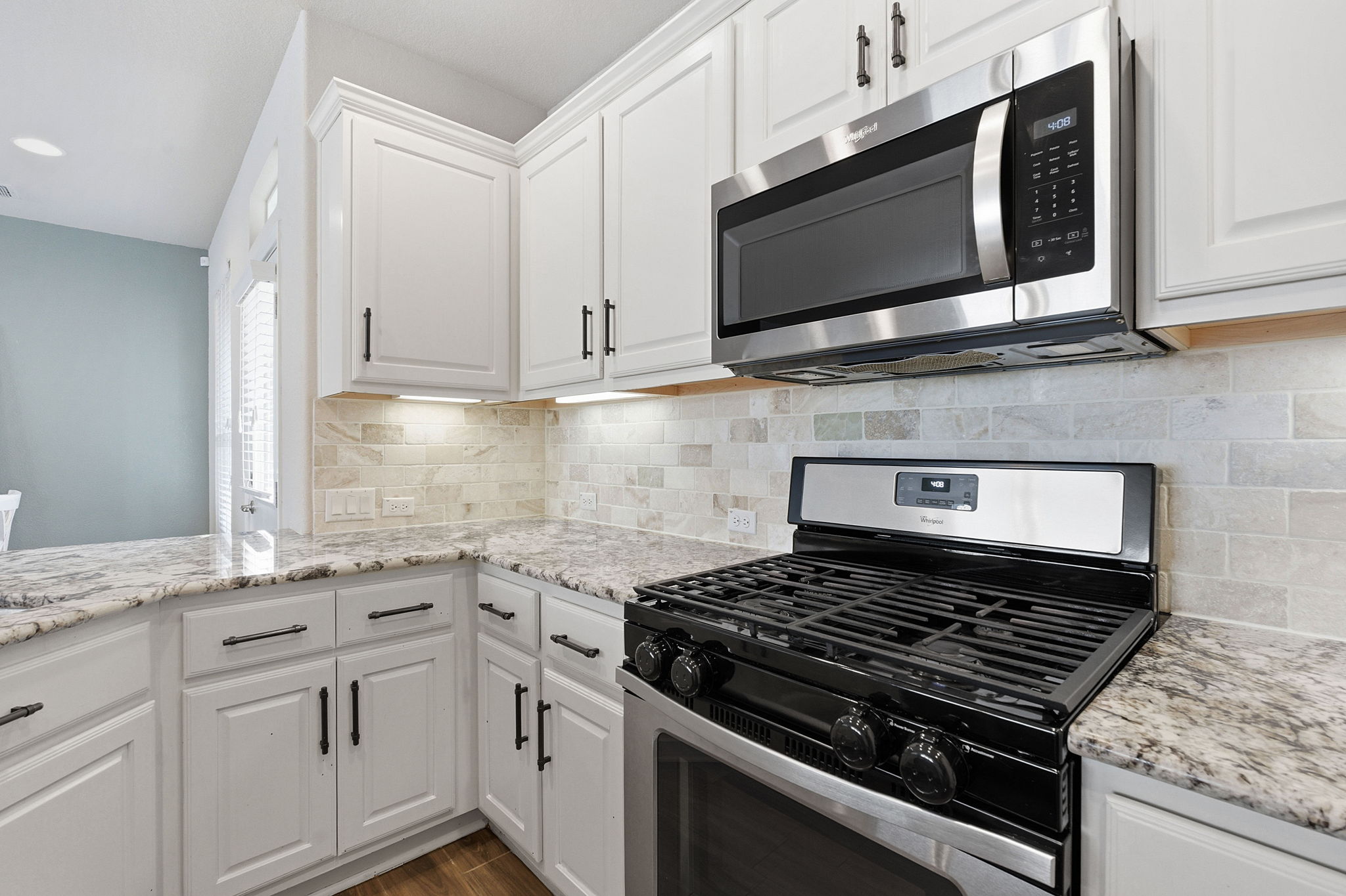 6005 Baythorne Drive Austin, TX 78747 - Photo 9 of 40 Kitchen with stainless steel appliances, white cabinetry, light stone countertops, tasteful backsplash, and dark wood-style flooring