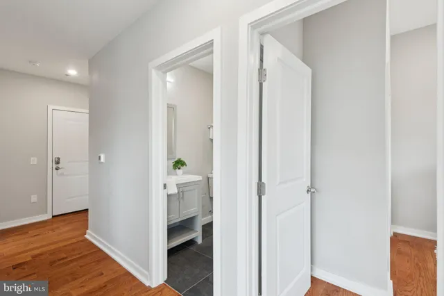 a view of a hallway with bathroom and wooden floor