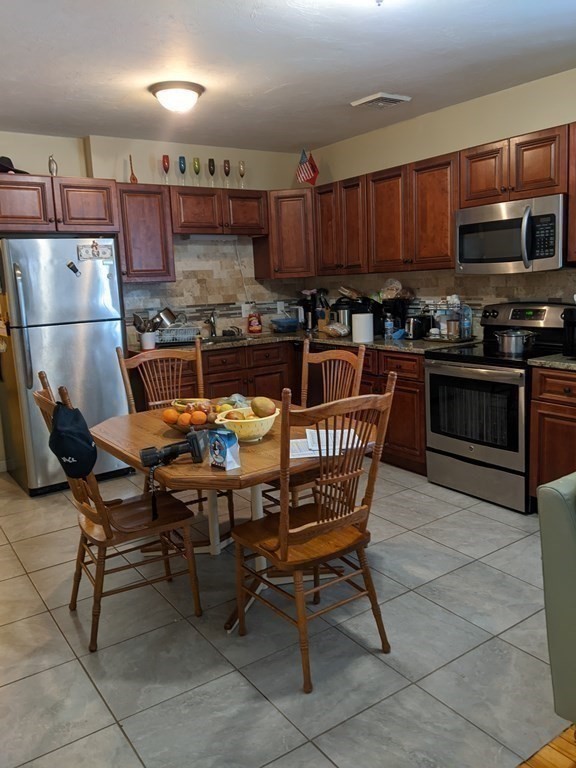 121 Winfield Street Worcester, MA 01602 - Photo 14 of 42 a kitchen with stainless steel appliances granite countertop a table chairs microwave and sink